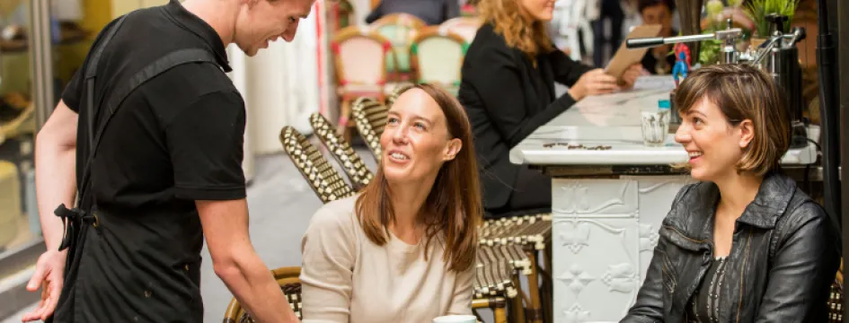 Waiter serving sandwiches to two women in laneway cafe